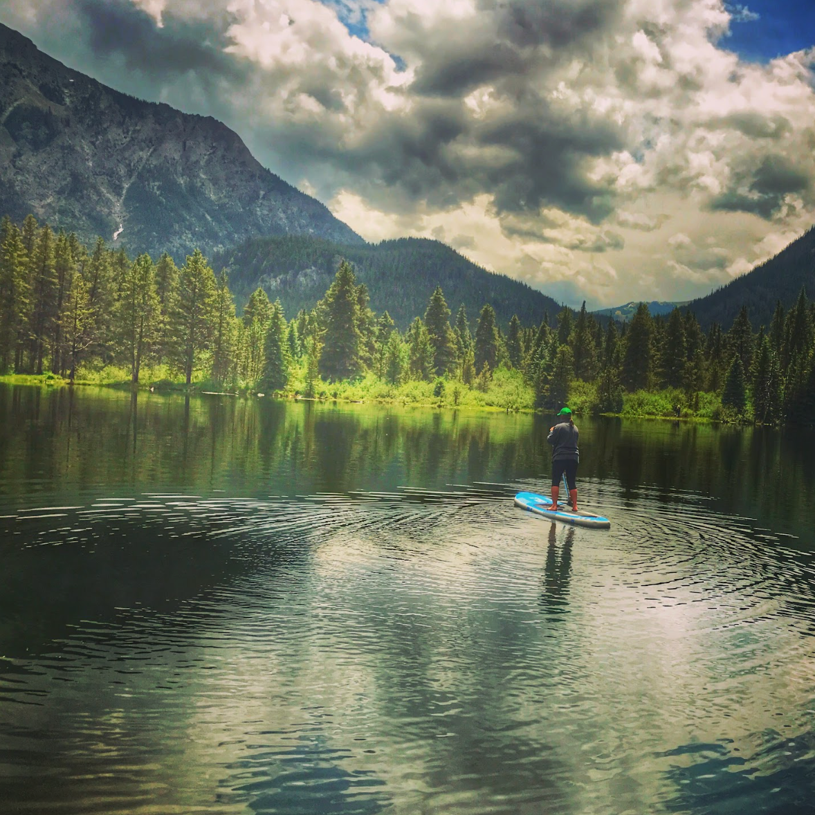 casey paddle boarding in nature on a lake at ripple and root therapy in colorado