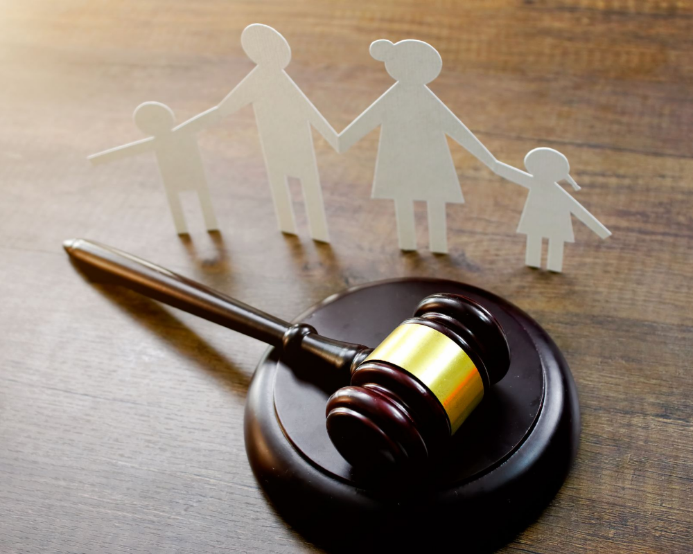 A Wooden Gavel Is Sitting On A Wooden Table Next To A Paper Cut Out Of A Family — Kingsport, TN — Francisco & Harr