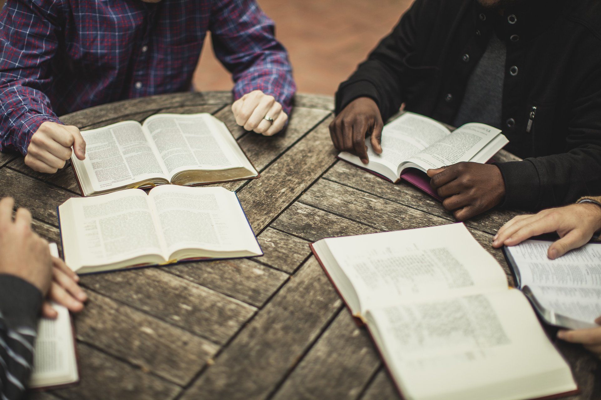 A group of people are sitting around a table reading books.