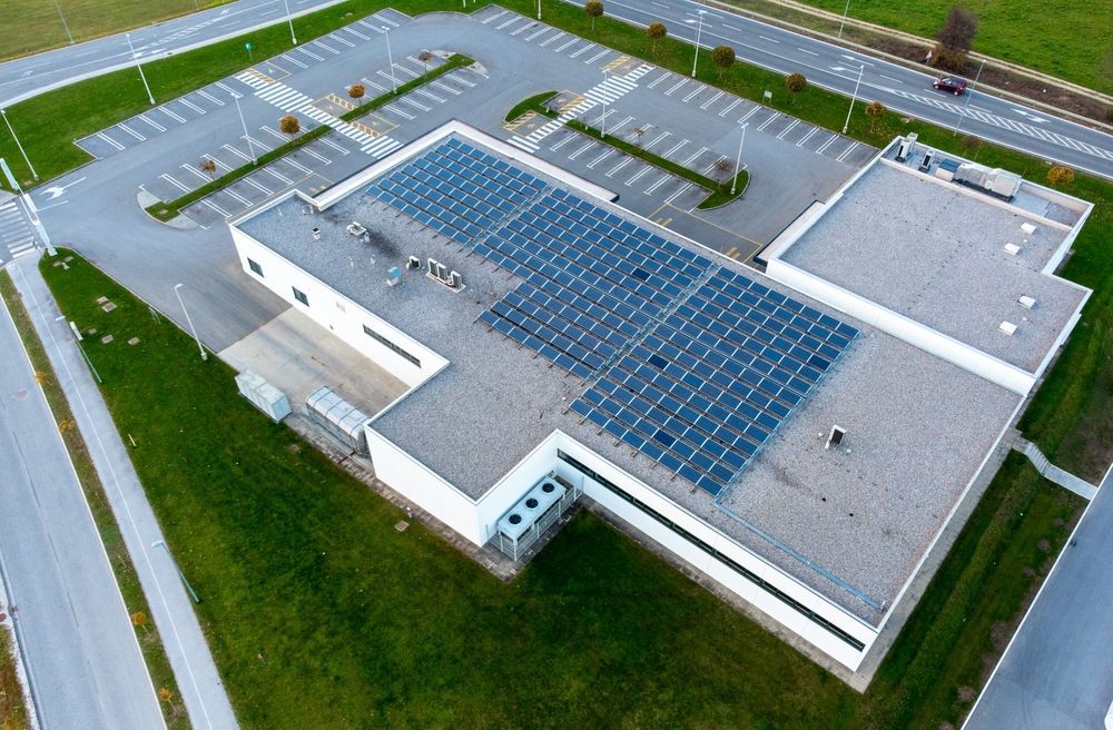 Aerial view of a large industrial building with a rooftop covered in solar panels