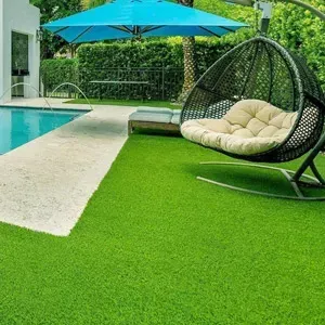 Poolside patio with green turf, blue umbrella, and hanging egg chair beside the water
