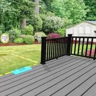 Wooden deck overlooking a green backyard with a white shed and landscaped shrubs.