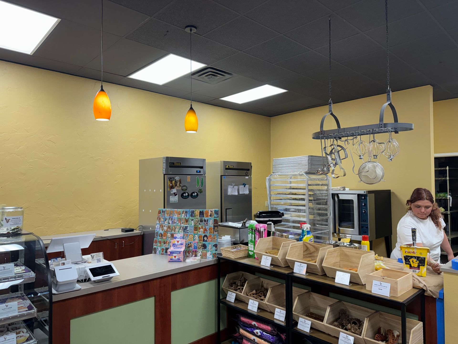 A woman is standing at a counter in a bakery talking on a cell phone.