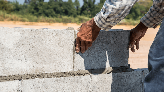 “Worker carefully placing concrete blocks by hand to build a sturdy wall during concrete services in Casas Adobes, AZ”