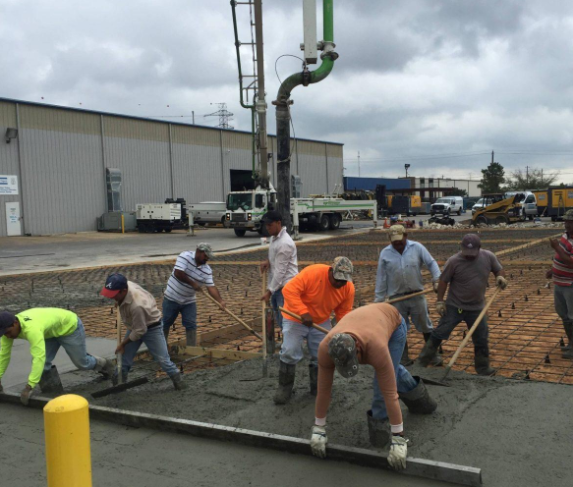 “Crew guiding fresh concrete from a pump hose into a large commercial slab area by a concrete contractor in Casas Adobes, AZ”