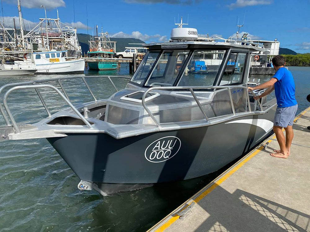 A man is standing next to a boat docked at a dock.