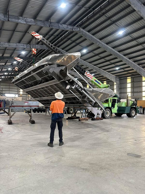Man is Standing in a Warehouse Looking at a Boat — BME NQ in Portsmith, QLD