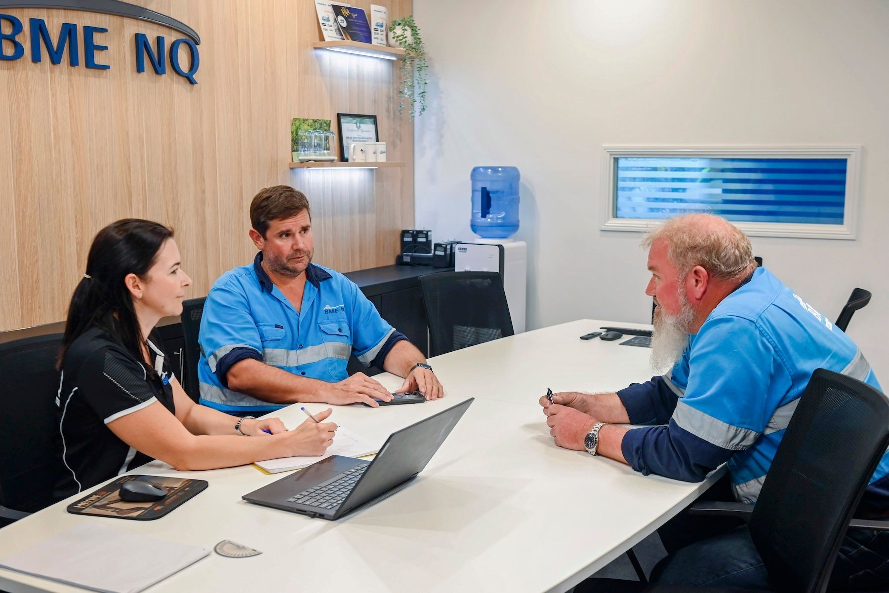 A group of people are sitting around a table with a laptop.