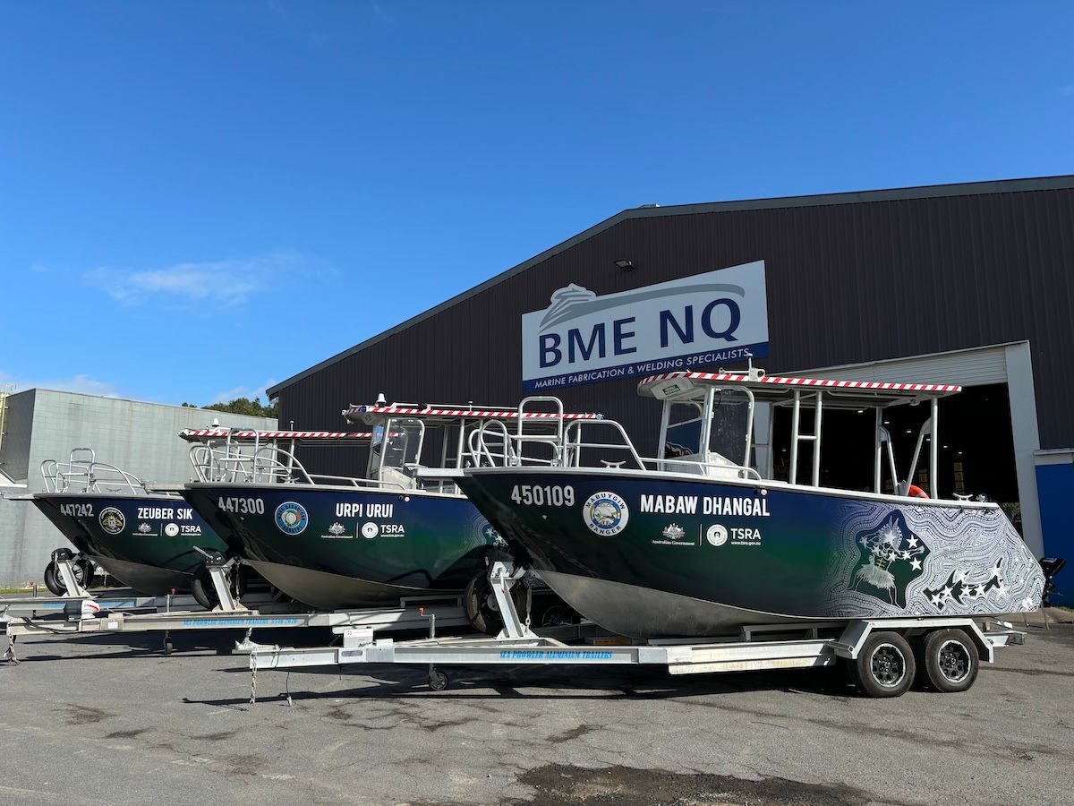 Three boats are parked in front of a building that says bme no.