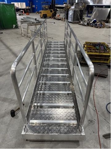 A metal staircase with a railing is being built in a factory.