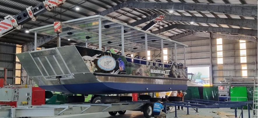 A large boat is being built in a large warehouse.