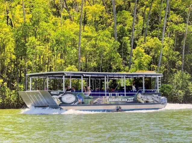 A boat is floating on top of a body of water surrounded by trees.