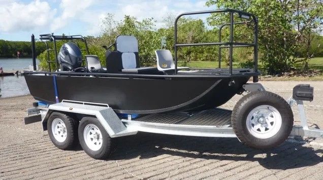 A boat is on a trailer next to a lake