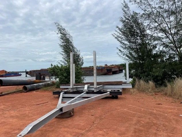 A trailer is sitting in the middle of a dirt field.