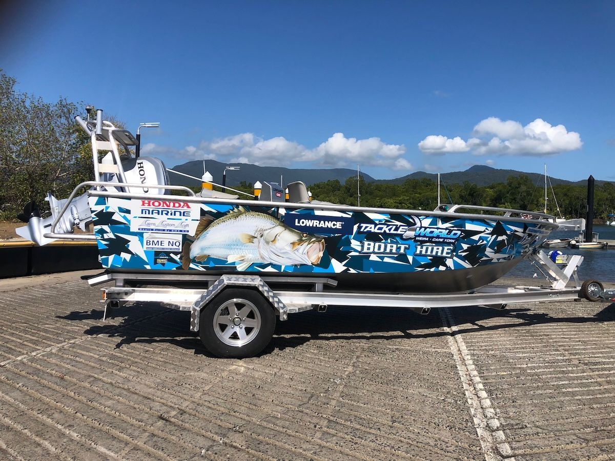 A boat is sitting on a trailer in a parking lot.