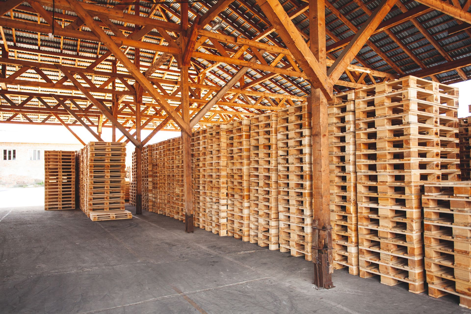 A warehouse filled with wooden pallets under a wooden roof