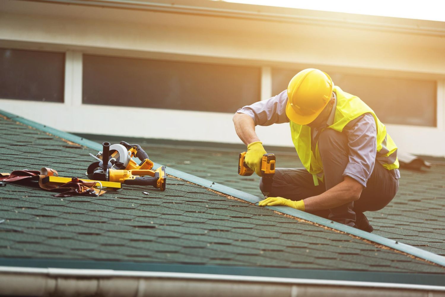 A man is working on a roof with a drill.