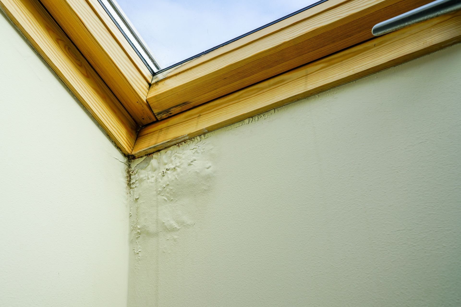 Skylight in a room with water damage visible on the wall and wood trim.