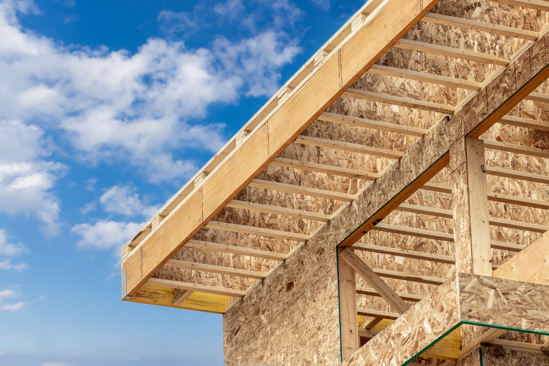 Partially built house roof with wooden trusses against a blue sky