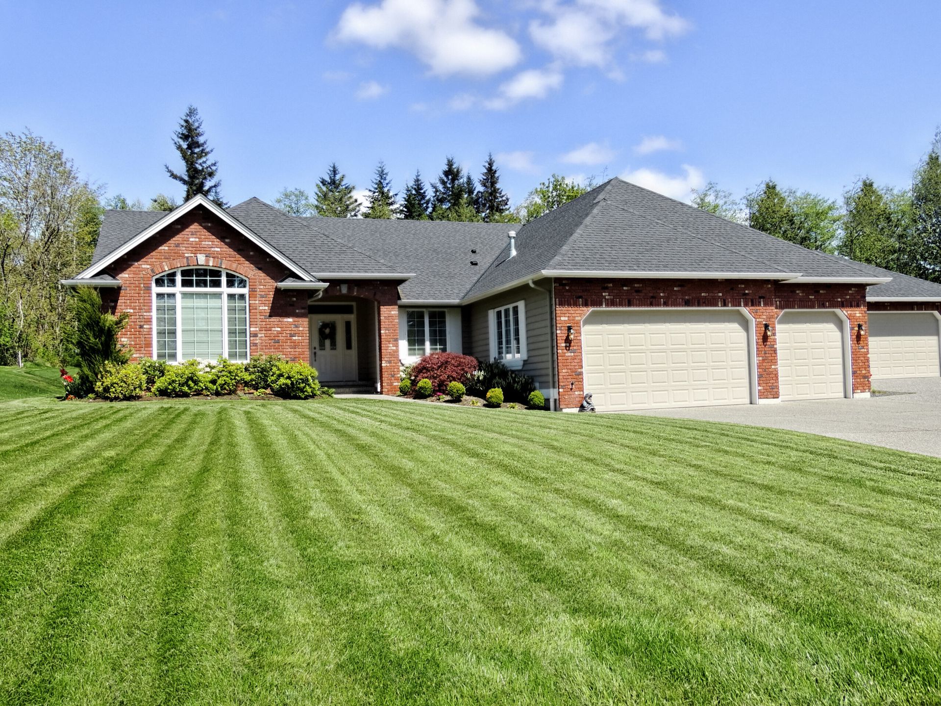 A large brick house with a lush green lawn in front of it.