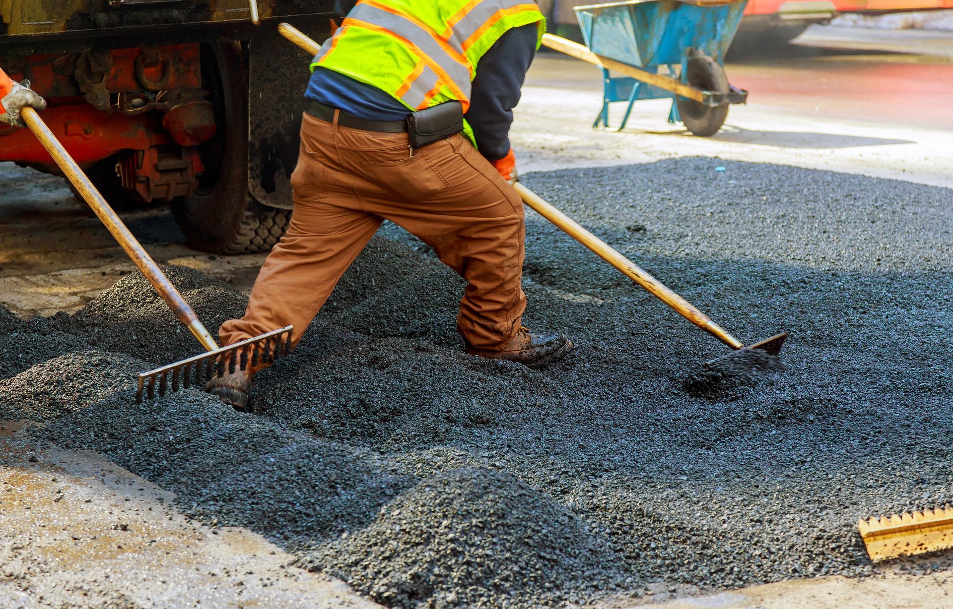 A construction worker is raking gravel 