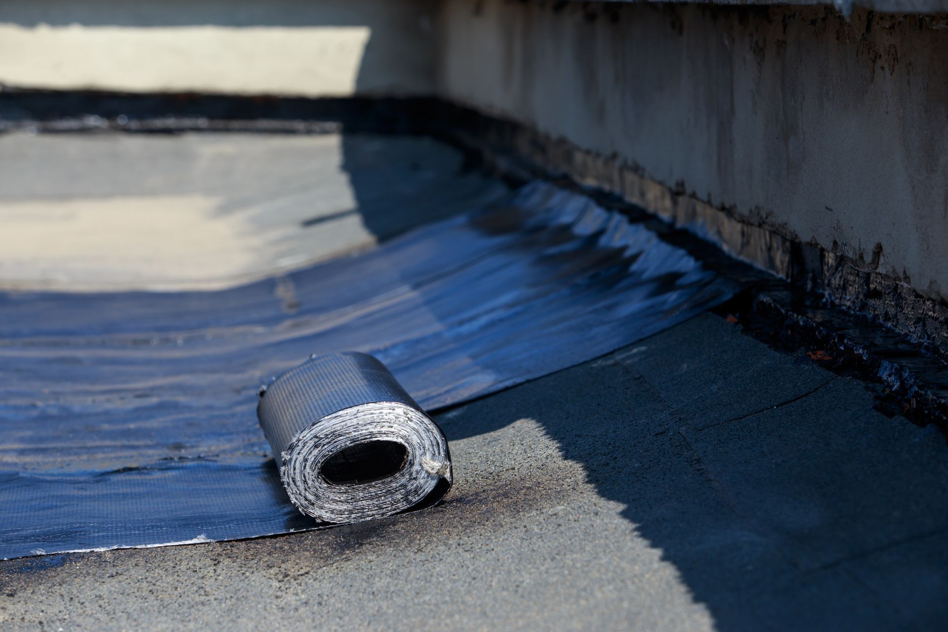 A roll of waterproofing tape is being applied to a roof.
