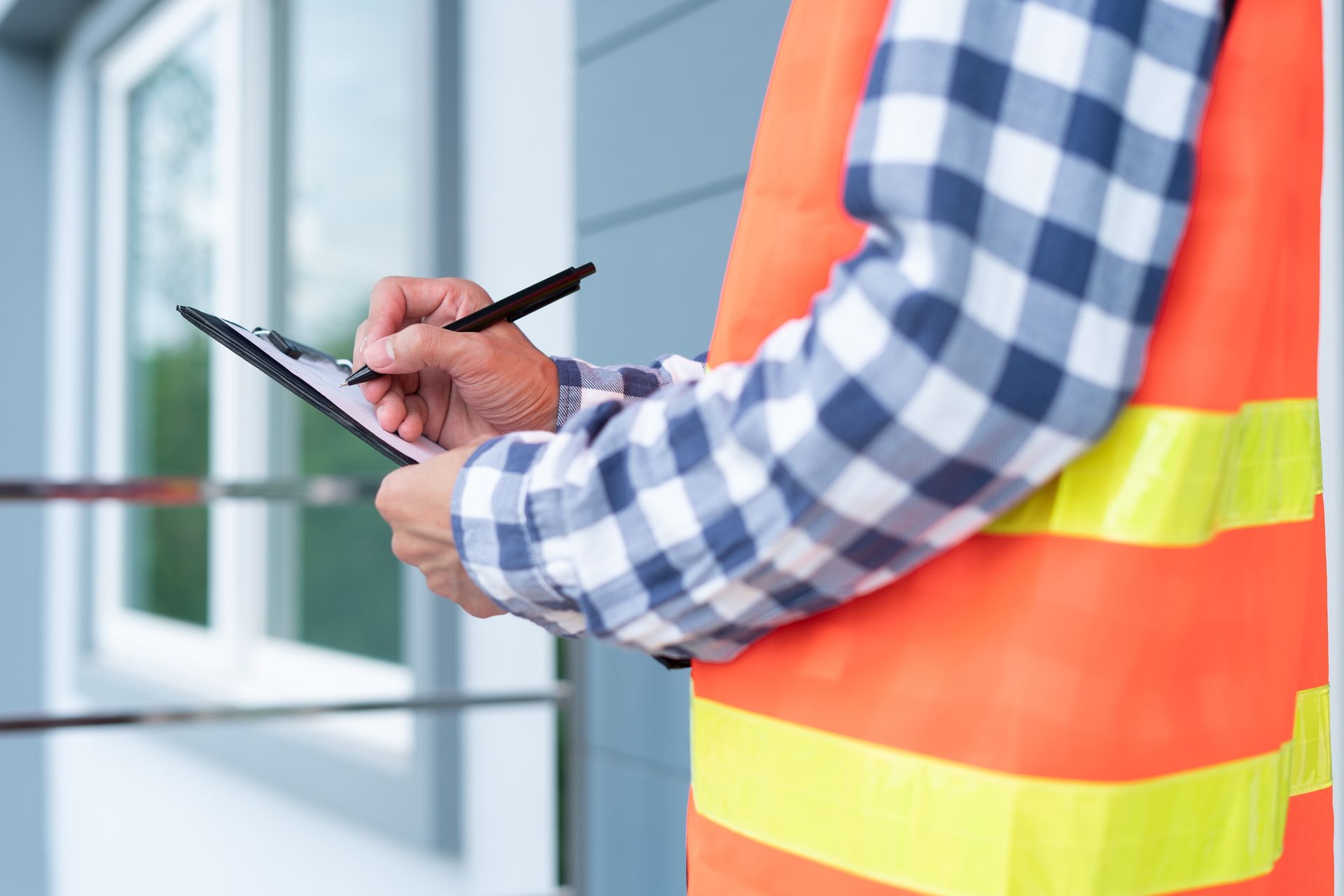 A construction worker is writing on a clipboard with a pen.