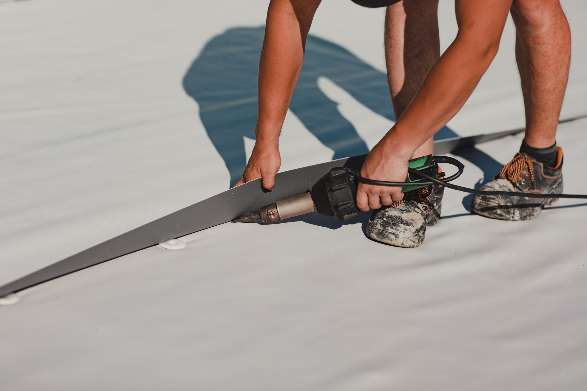 A man is cutting a piece of foam with a saw on a roof.