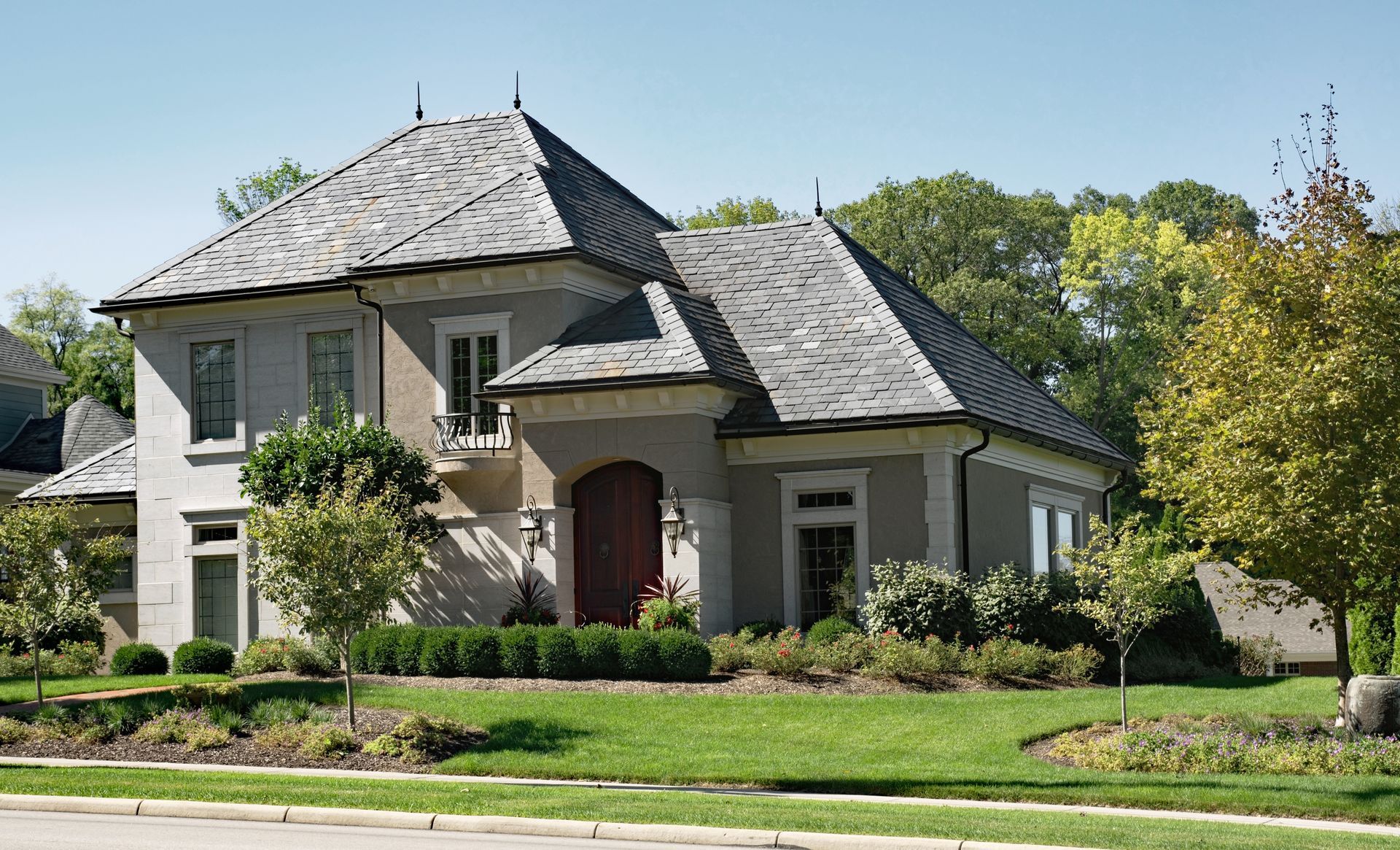 A large house with a slate roof is sitting on top of a lush green lawn.