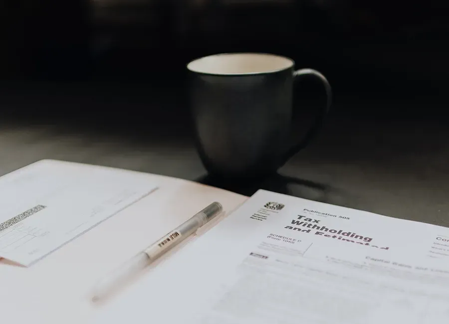 A  cup of coffee sitting on top of a table next to a piece of paper.