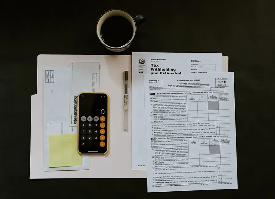 A calculator, a pen, and some papers on a table.