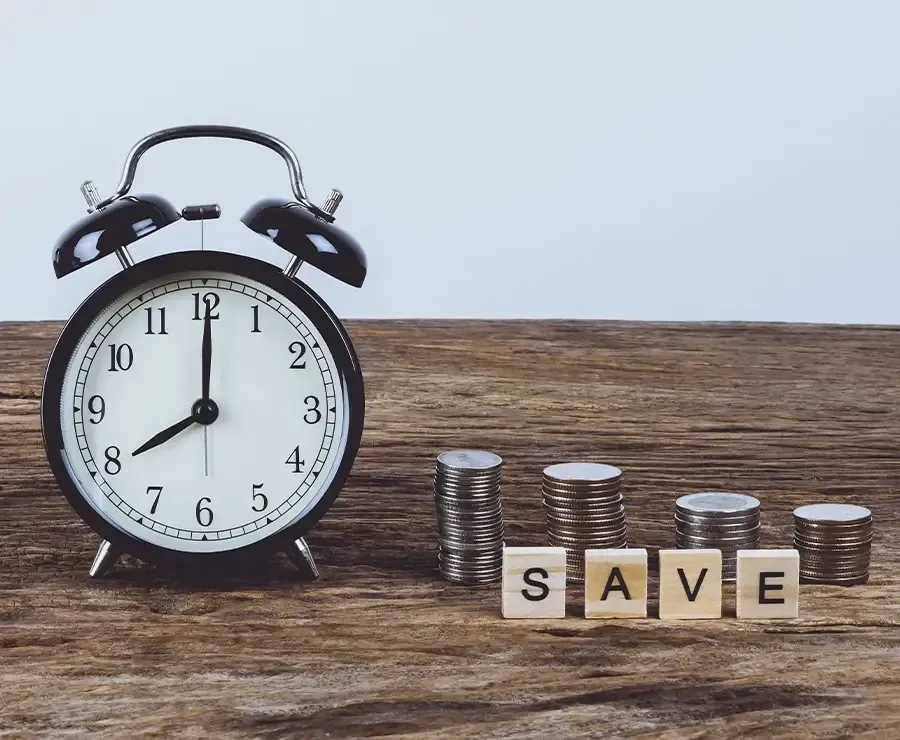 An alarm clock sitting next to stacks of coins.