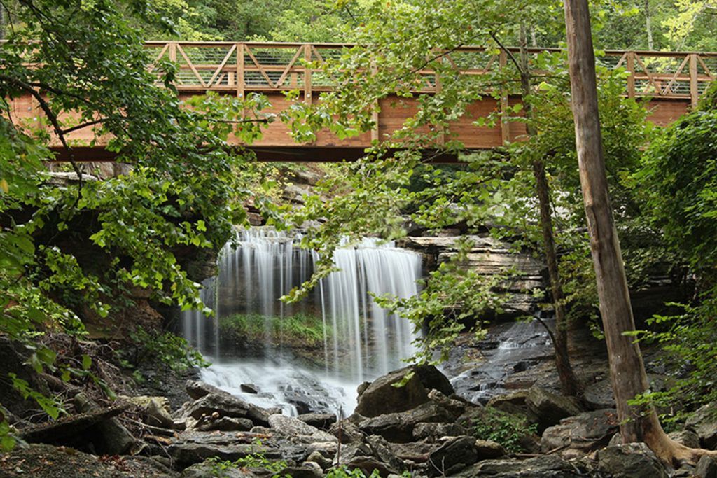 a wooden bridge over a waterfall in the woods