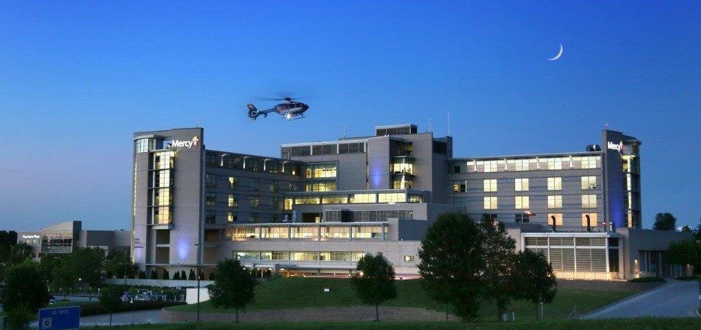 A helicopter is flying over a large building at night