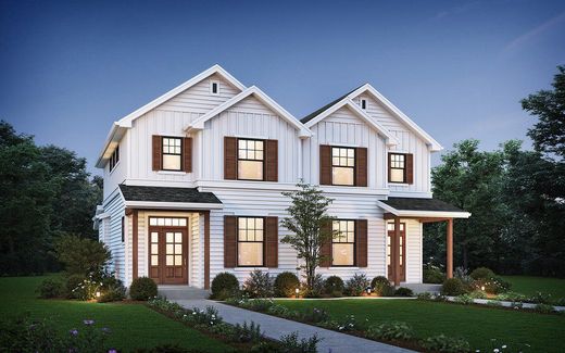 Two-story white farmhouse-style duplex with brown shutters and doors, on a grassy lot.