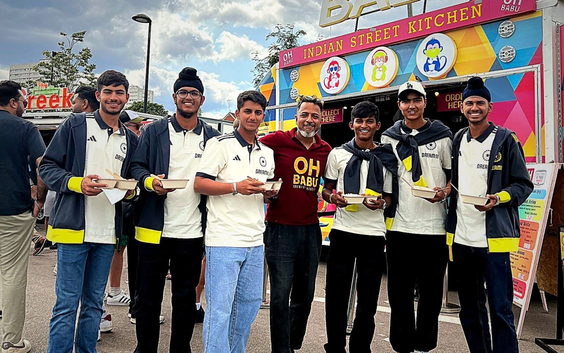 Group of people holding food in front of Oh Babu food truck. They appear happy and are smiling.