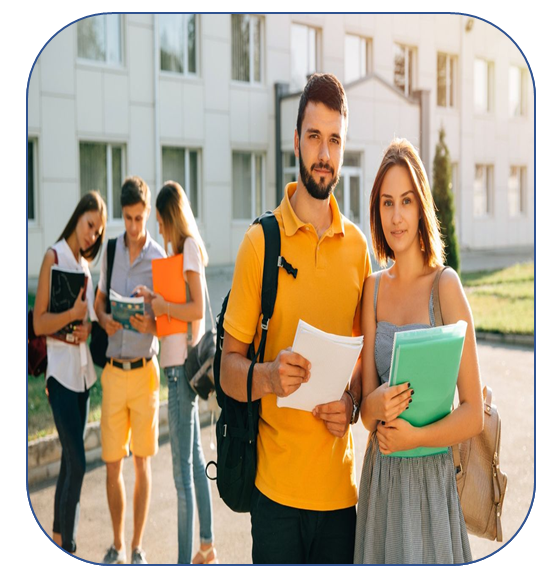 Cuatro estudiantes sosteniendo cuadernos se encuentran al aire libre frente a un edificio escolar en un día soleado.