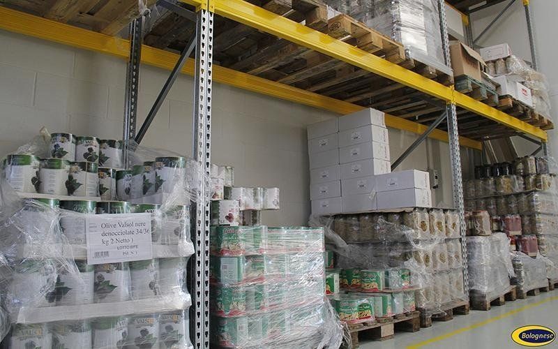 Interno di un magazzino con pallet di merci imballate impilate su scaffali.