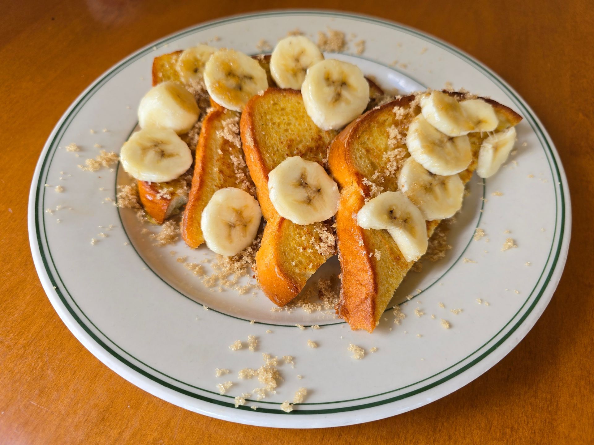 French toast with banana slices and sprinkled topping on a plate.