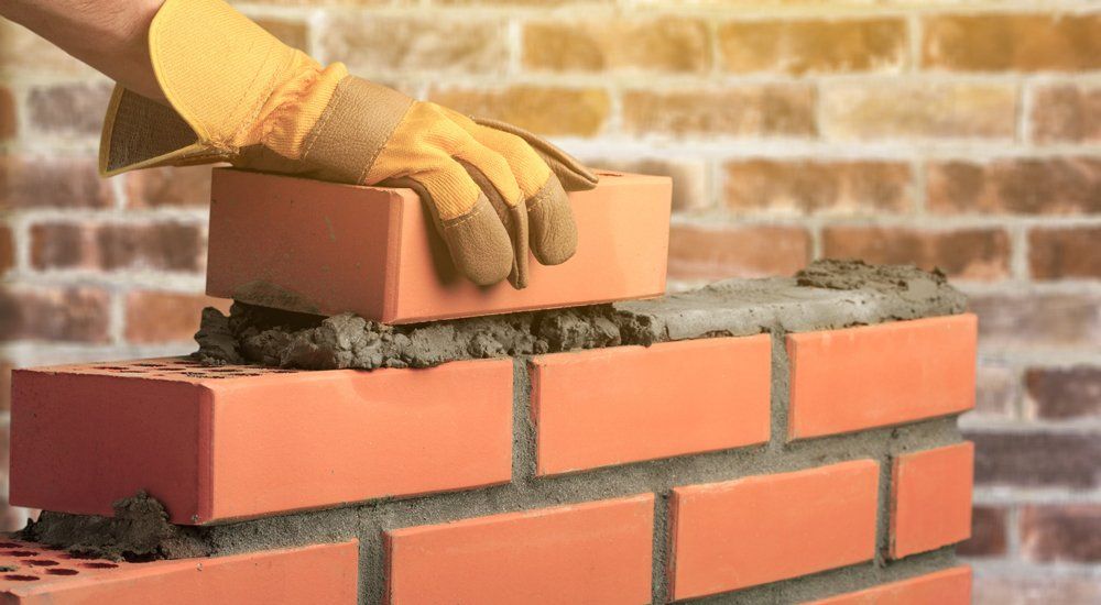 Stucco Exterior — Worker Builds a Brick Wall in Panama City, FL
