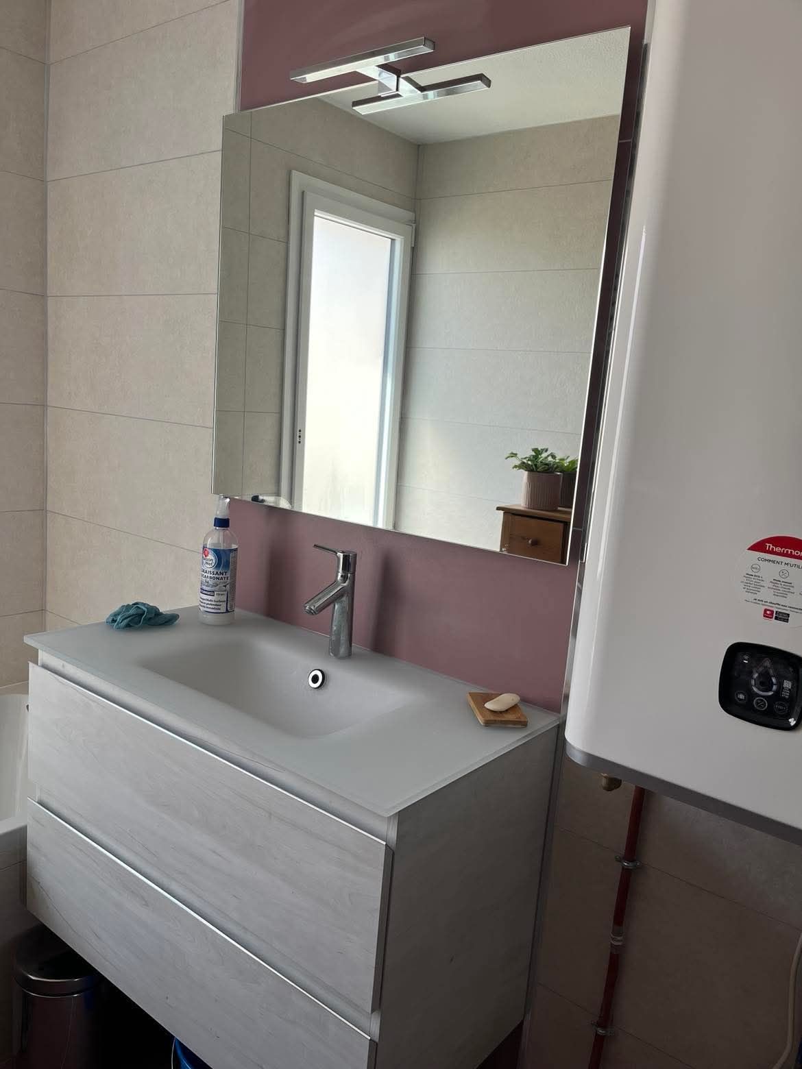 Une salle de bain avec lavabo, baignoire, miroir et porte-serviettes.