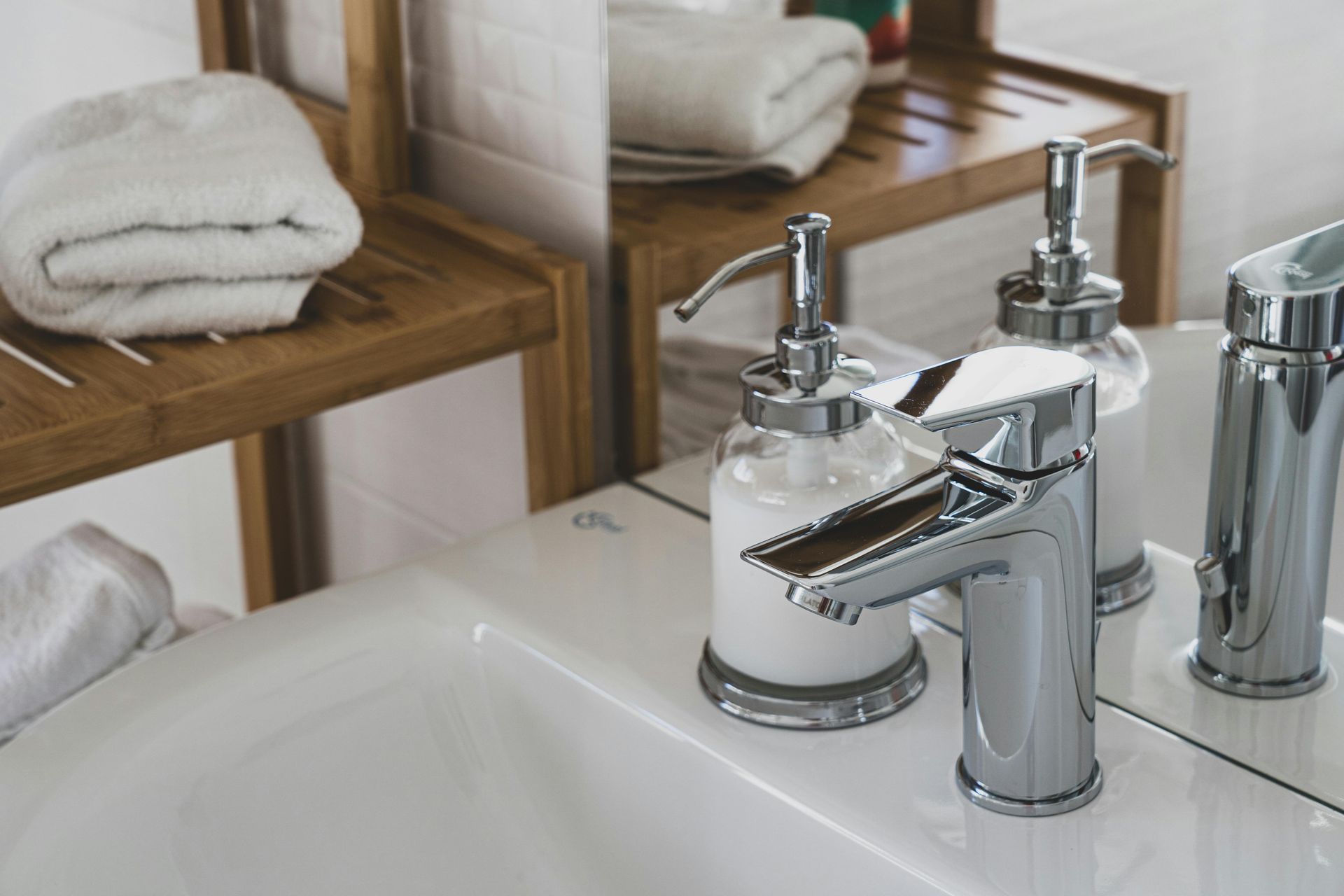 Un lavabo de salle de bain avec deux distributeurs de savon et un miroir.