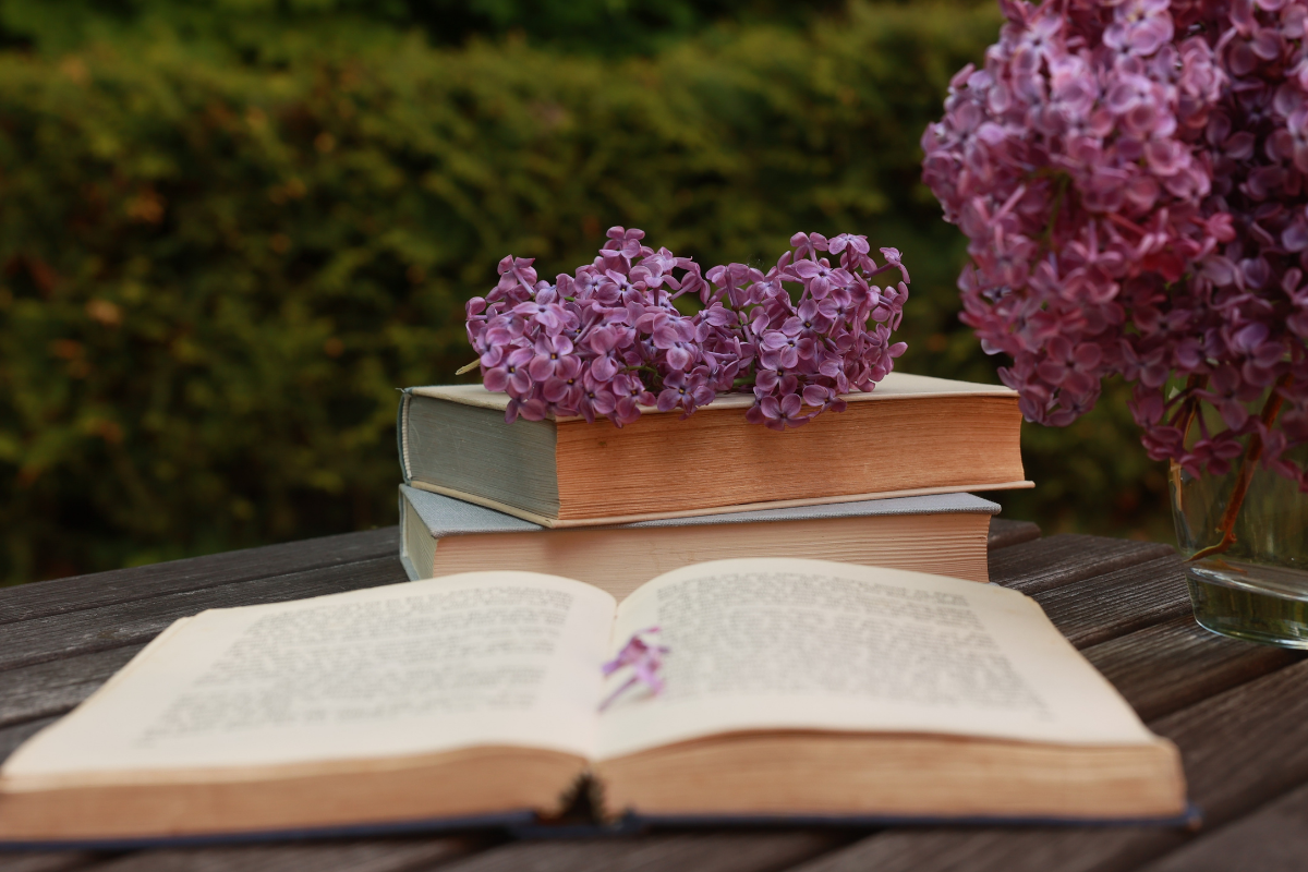 book and lilacs laid out on a table outside 