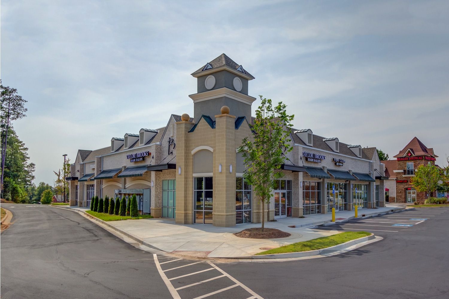 Commercial building with gray tower, beige brick exterior, and multiple storefronts. Commercial Plumber in Dacula Georgia.