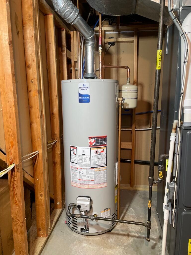 Water heater inside a framed wall; metal flue, gas pipes, and a water tank.