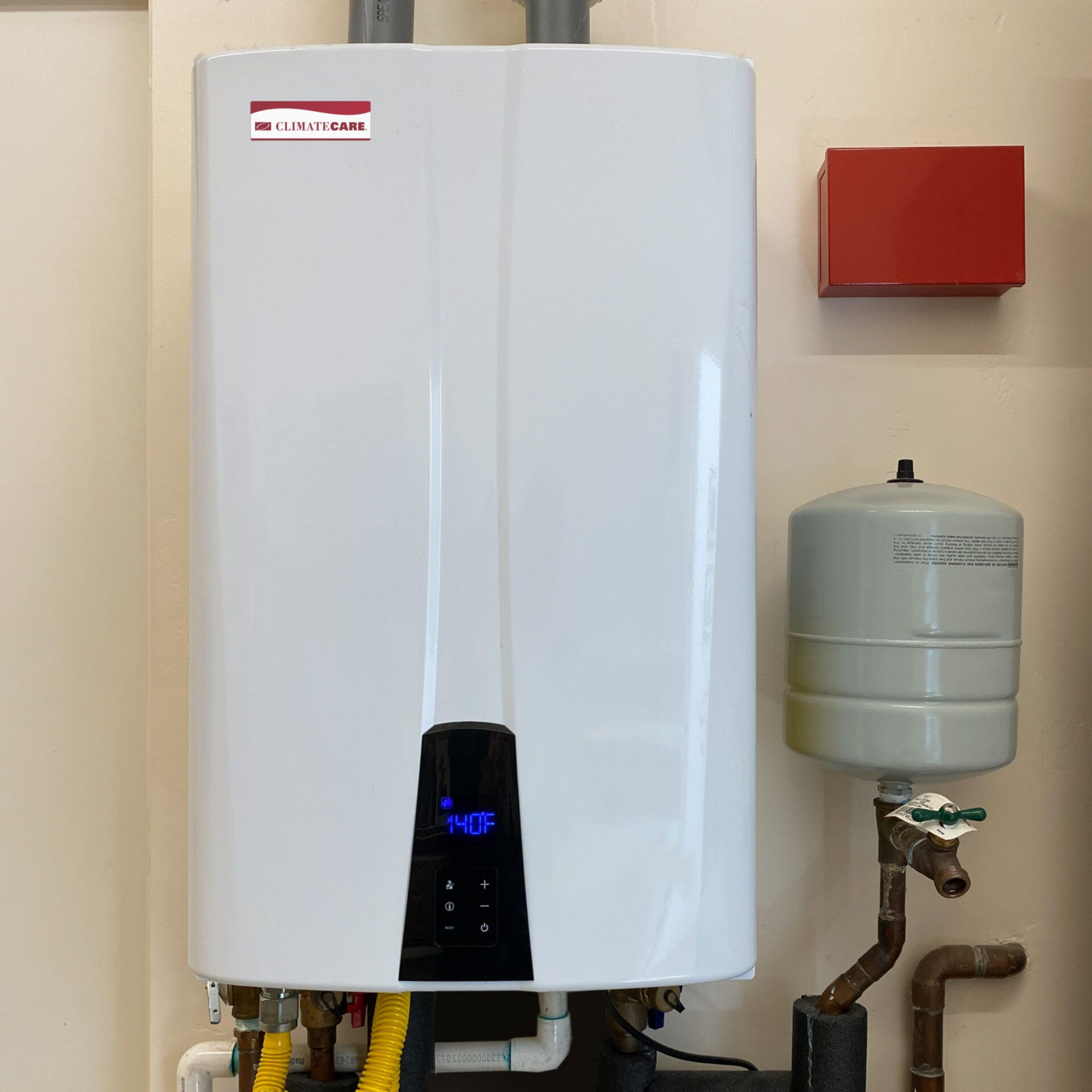 White wall-mounted water heater with a black control panel, pipes, and an expansion tank. Tankless water heater for house.