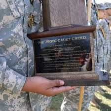 Person in camo holding JROTC Cadet Creed plaque.