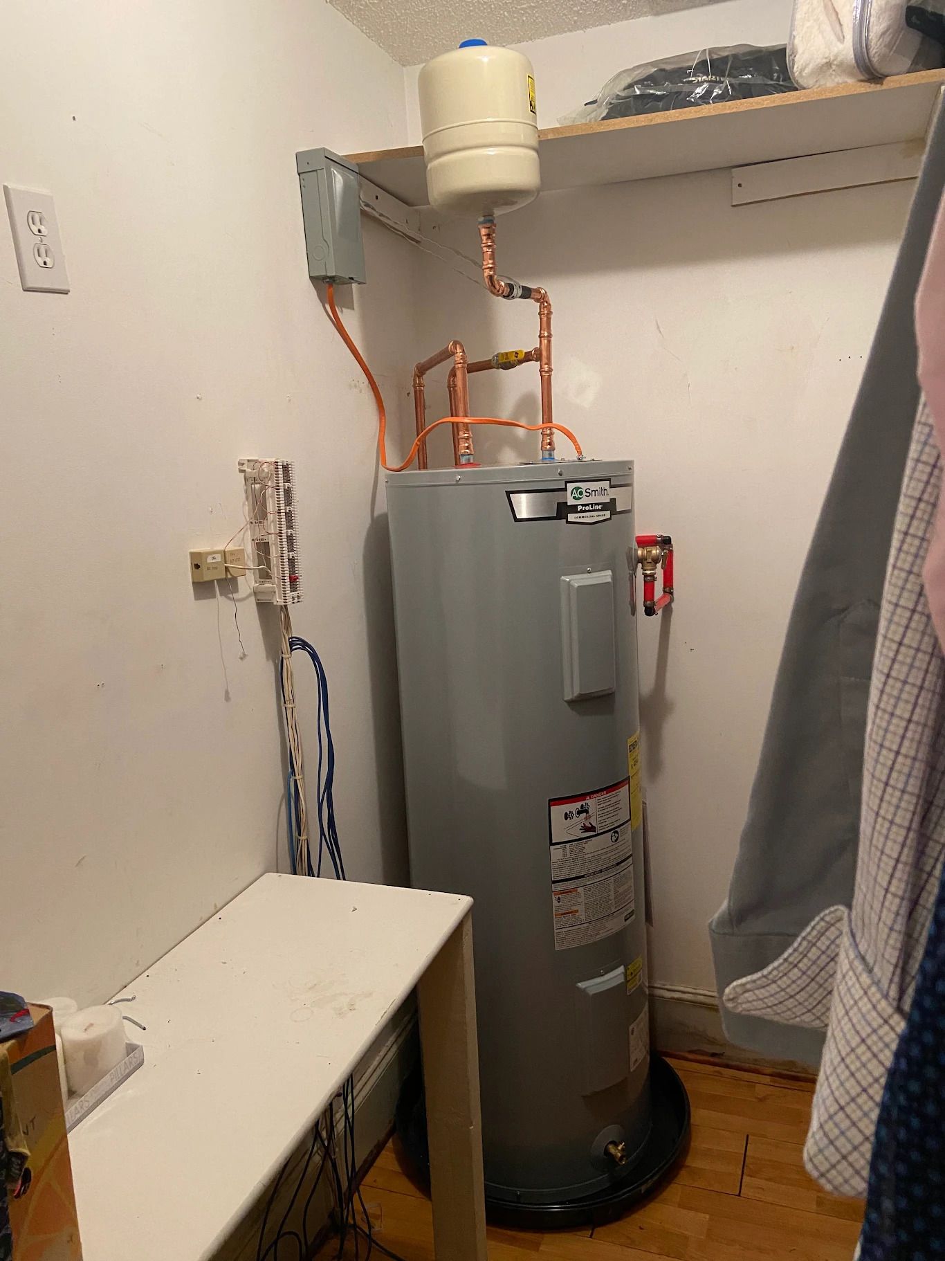 Water heater inside a framed wall; metal flue, gas pipes, and a water tank.