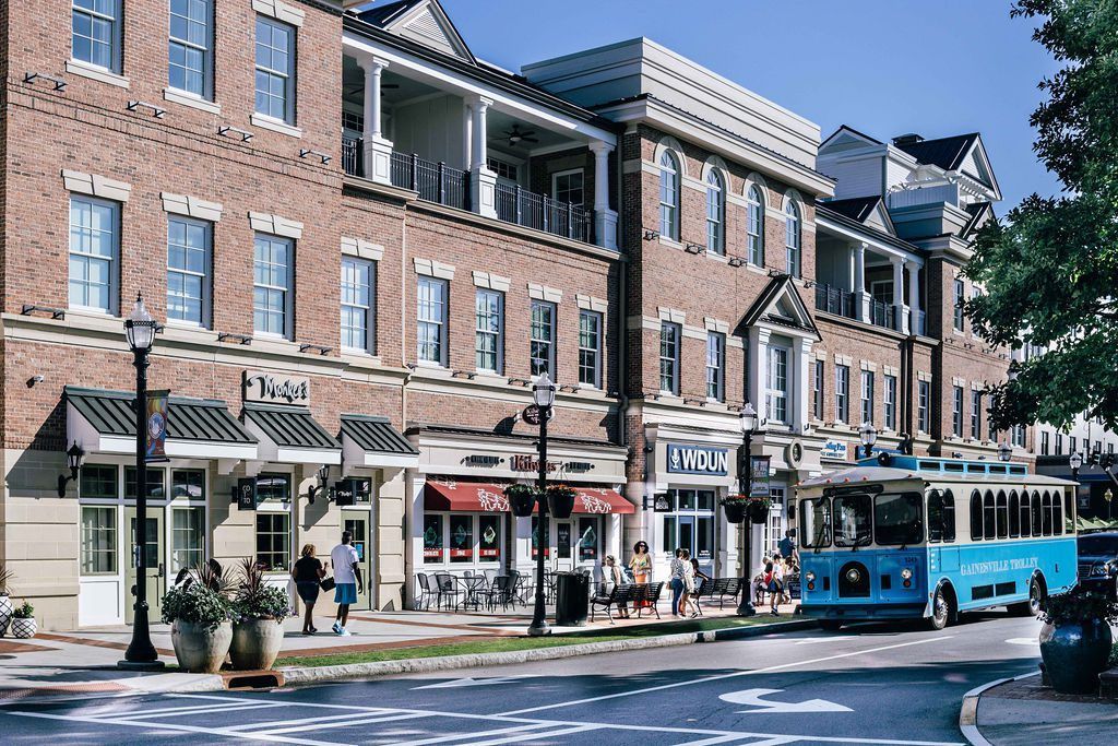 Shops and restaurants line a brick building, a blue trolley on the street. Commercial plumber in Gainesville GA for office.