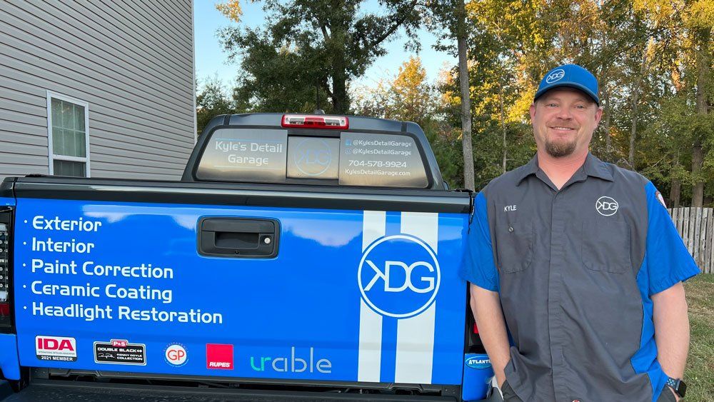 A man is standing in front of a blue truck.